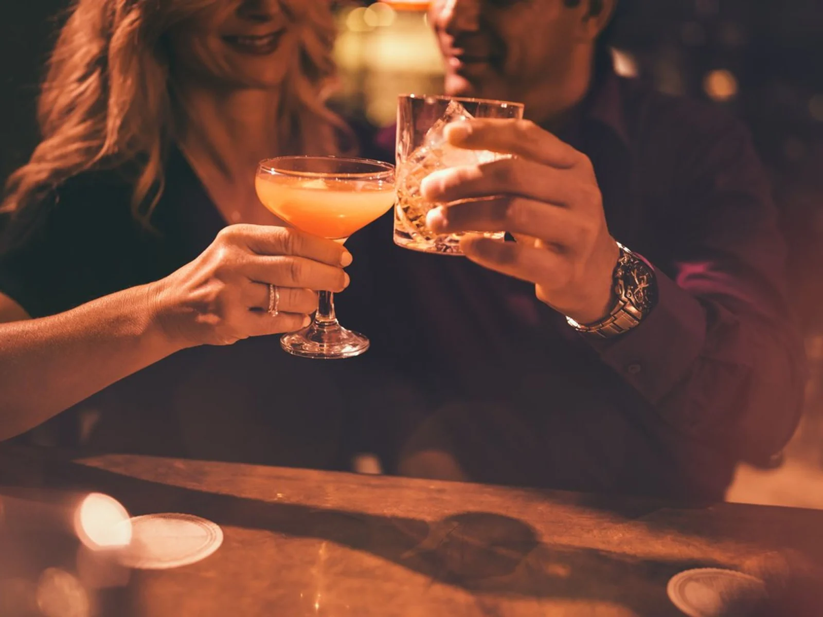 Couple clinking glasses at a dimly lit bar.