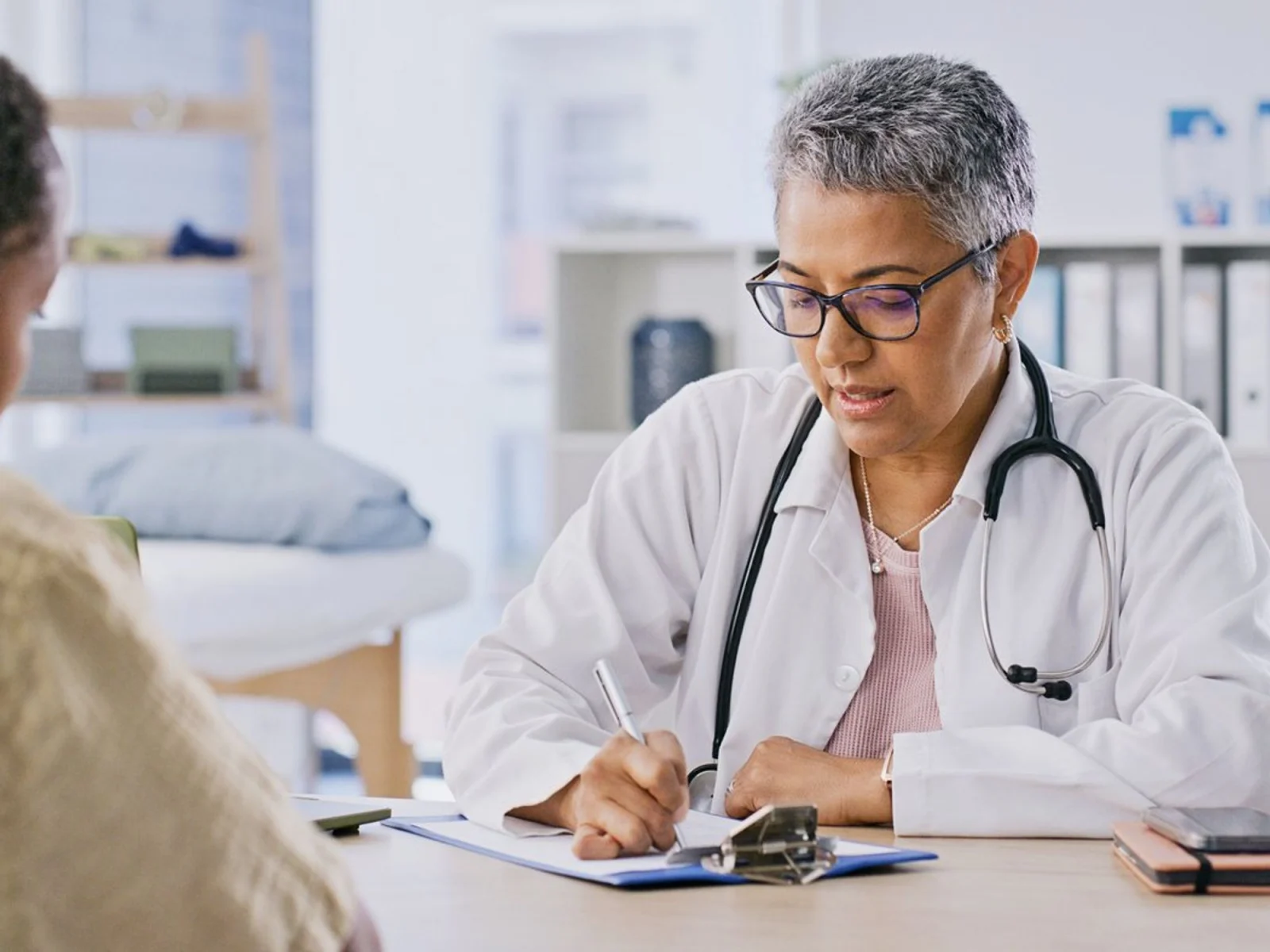 Doctor writing notes during patient consultation.