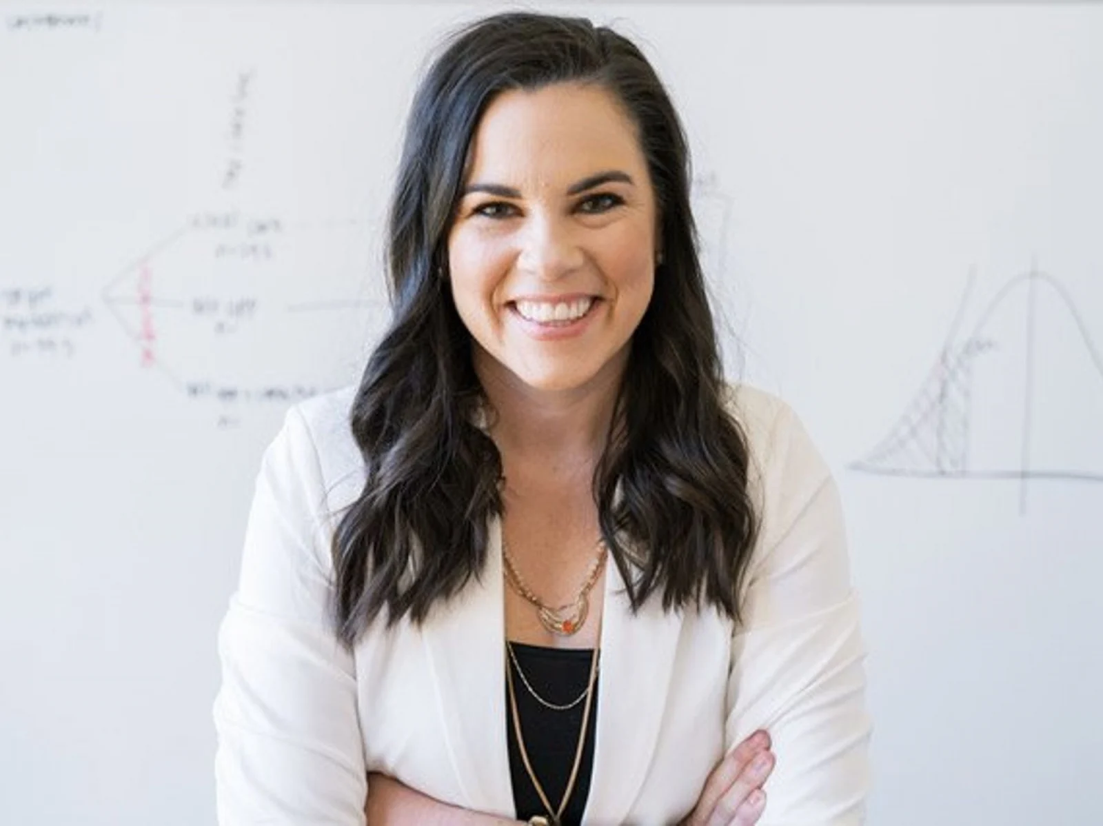 Smiling woman in office with whiteboard.