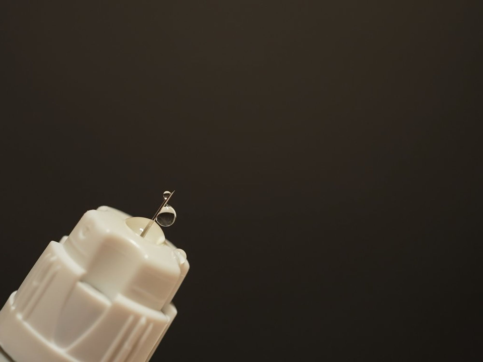 Needle with liquid droplet on dark background