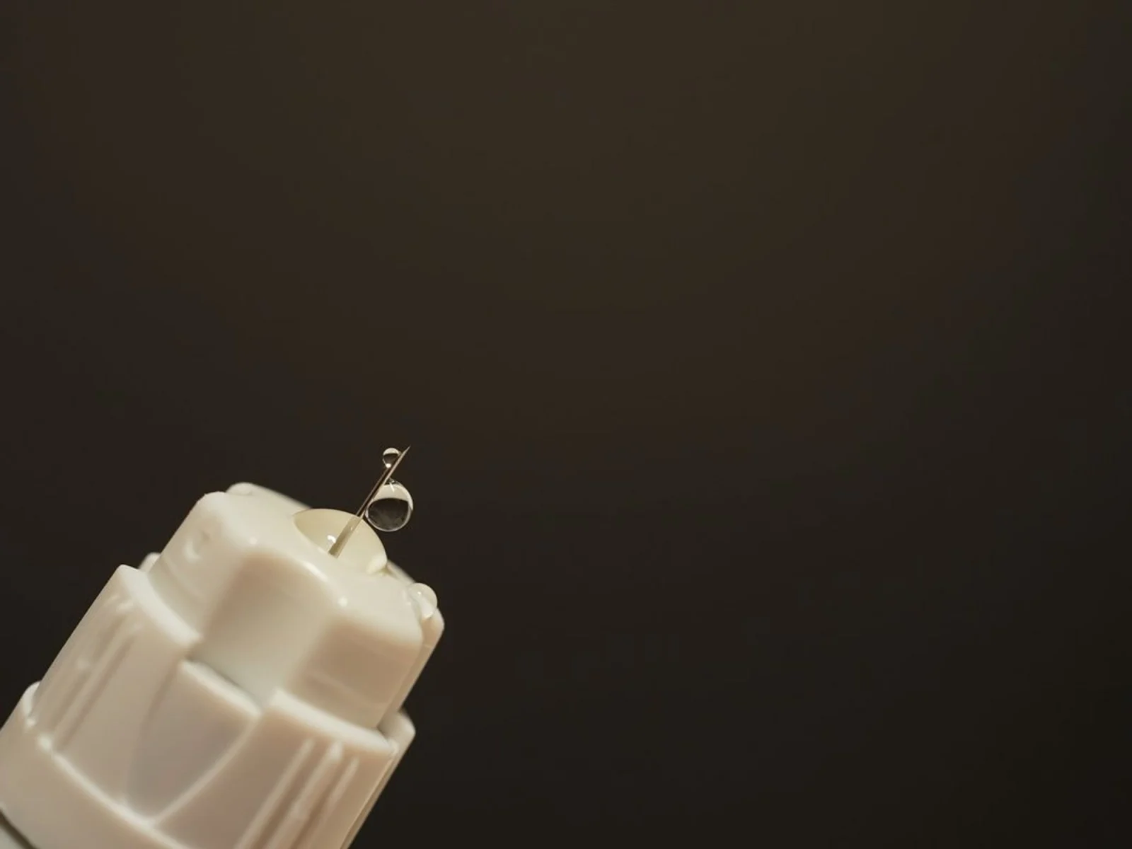 Needle with liquid droplet on dark background
