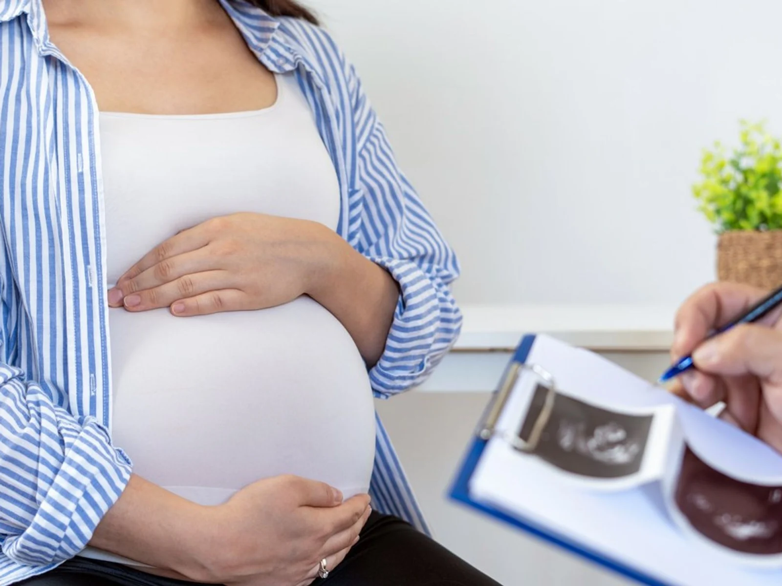 Pregnant woman at doctor's appointment holding belly.