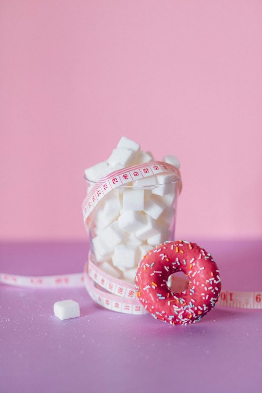 sugar and donut with measuring tape representing metabolism and weight gain